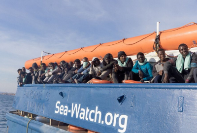 Statek z migrantami stoi naprzeciwko portu na wyspie Lampedusa